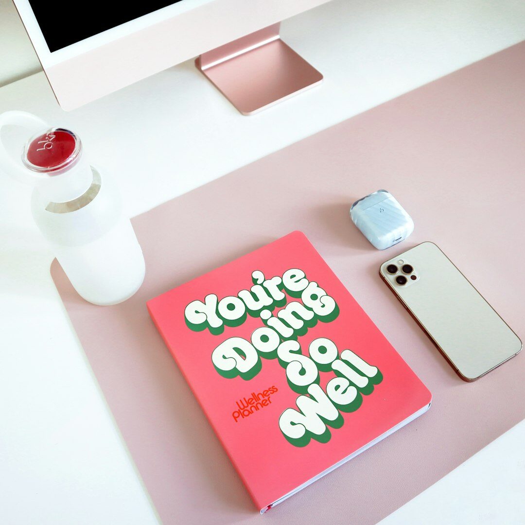 Person writing in a notebook at a clean desk with a cup of coffee